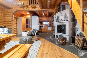 A log cabin interior with a stone fireplace, wooden furniture, and a cozy seating area.