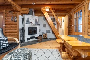 A log cabin interior with a fireplace, a dining table, and a staircase.
