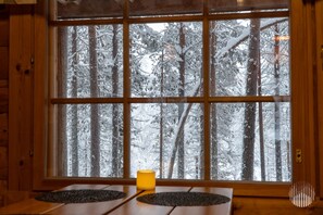A room with a large window offering a view of a snowy forest.