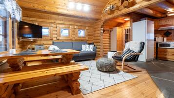 L’intérieur d’une cabane en rondins comprend un coin repas, un canapé et une cuisine.
