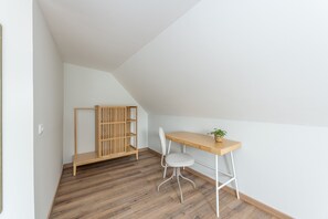 A room with a sloped ceiling, a wooden desk with a chair, a small plant, and a wooden cabinet. - Nomad s Family - 2bdr The Docks in Porto (Porto)