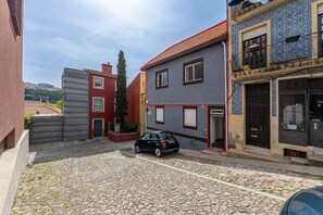 A cobblestone street with buildings, a parked car, and a clear sky. - Nomad s Family - 2bdr The Docks in Porto (Porto)