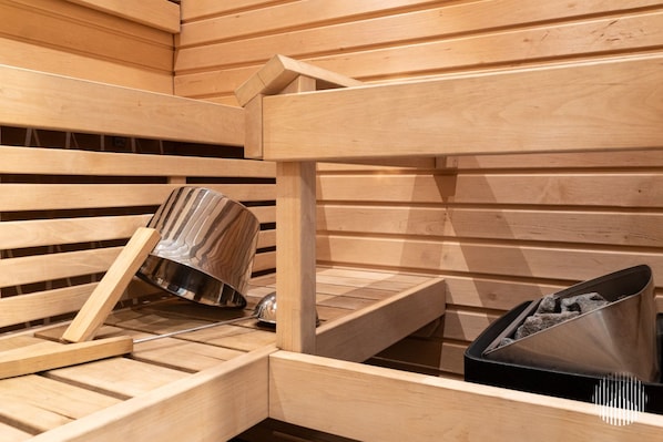 A sauna with wooden benches and a metal container for ashes. - Sivulantie 4 206 by Holiday in Lapland (Äkäslompolo)
