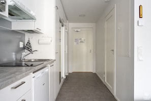 A narrow hallway with a kitchen area on one side, featuring a sink, cabinets, and a stove. - Sivulantie 4 206 by Holiday in Lapland (Äkäslompolo)