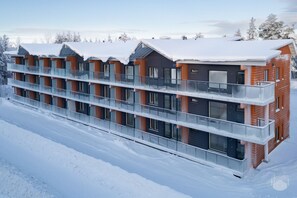 Un hotel de varios pisos con balcones y ventanas grandes, rodeado de nieve.