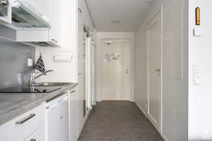 A narrow hallway with a kitchen area on one side, featuring a sink, cabinets, and a stove. - Ylläs Sivulantie 4 203 by Holiday in Lapland (Äkäslompolo)