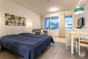 A hotel room with a bed, a desk, a chair, a television, and a window with curtains. - Ylläs Sivulantie 4 203 by Holiday in Lapland (Äkäslompolo)
