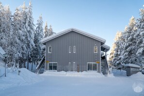 Ein großes, eingeschossiges Gebäude mit geneigtem Dach, umgeben von schneebedeckten Bäumen.