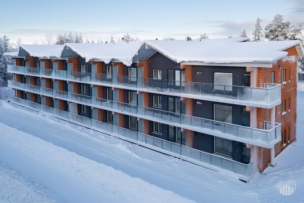 Ein mehrstöckiges Hotel mit Balkonen und großen Fenstern, umgeben von Schnee.