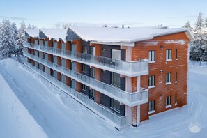 Ein mehrstöckiges Gebäude mit Balkonen, umgeben von schneebedeckten Bäumen.