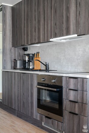 Een moderne keuken met donker houten kastjes, een roestvrijstalen aanrechtblad en een ingebouwde oven.