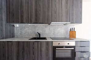 A kitchen with dark wood cabinets, a stainless steel sink, a built-in oven, and a knife block. - Äkäsentie 1 A 208 by Holiday in Lapland (Äkäslompolo)