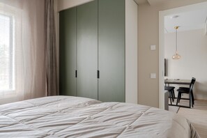 Een slaapkamer met een bed, een kledingkast, een bureau met stoelen en een hanglamp.