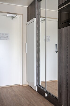 Ein Zimmer mit einer Schiebetür, einer Mikrowelle und Holzboden.