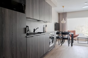 Eine moderne Küche mit dunklen Holzausführungen, einem Gasherd und einem Essbereich mit Tisch und Stühlen.