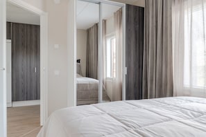 Un dormitorio con cama, armario y espejo.
