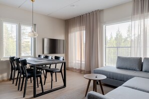 A modern living room with a dining area, a grey sofa, and a TV mounted on the wall. - Äkäsentie 1 A 313 by Holiday in Lapland (Äkäslompolo)