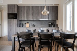 A modern kitchen with a central island, black chairs, and a hanging pendant light. - Äkäsentie 1 A 313 by Holiday in Lapland (Äkäslompolo)