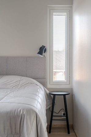 A bedroom with a bed, a bedside table, a lamp, and a window with blinds. - Äkäsentie 1 A 313 by Holiday in Lapland (Äkäslompolo)
