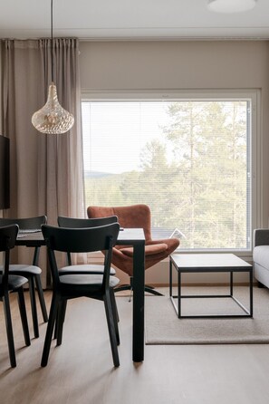 A modern living room with a dining area, a sofa, a brown armchair, a coffee table, and a large window with a view of trees. - Äkäsentie 1 A 301 by Holiday in Lapland (Äkäslompolo)