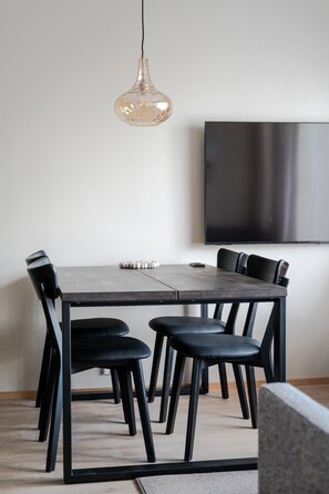 A modern dining area with a rectangular table, black chairs, a pendant light, and a flat-screen TV mounted on the wall. - Äkäsentie 1 A 301 by Holiday in Lapland (Äkäslompolo)