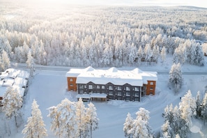 Un edificio grande rodeado de árboles cubiertos de nieve, probablemente un albergue o resort.