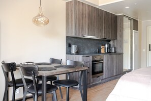 Une cuisine moderne avec un coin repas, comprenant une table avec des chaises, un luminaire suspendu et des appareils électroménagers intégrés.