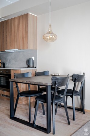 A modern kitchen with a wooden cabinet, a black countertop, and a hanging pendant light. - Äkäsentie 1 A 210 by Holiday in Lapland (Äkäslompolo)