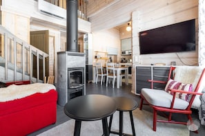 A modern interior with a fireplace, a dining area, and a TV mounted on the wall. - Revontuuli by Holiday in Lapland (Ylläs)