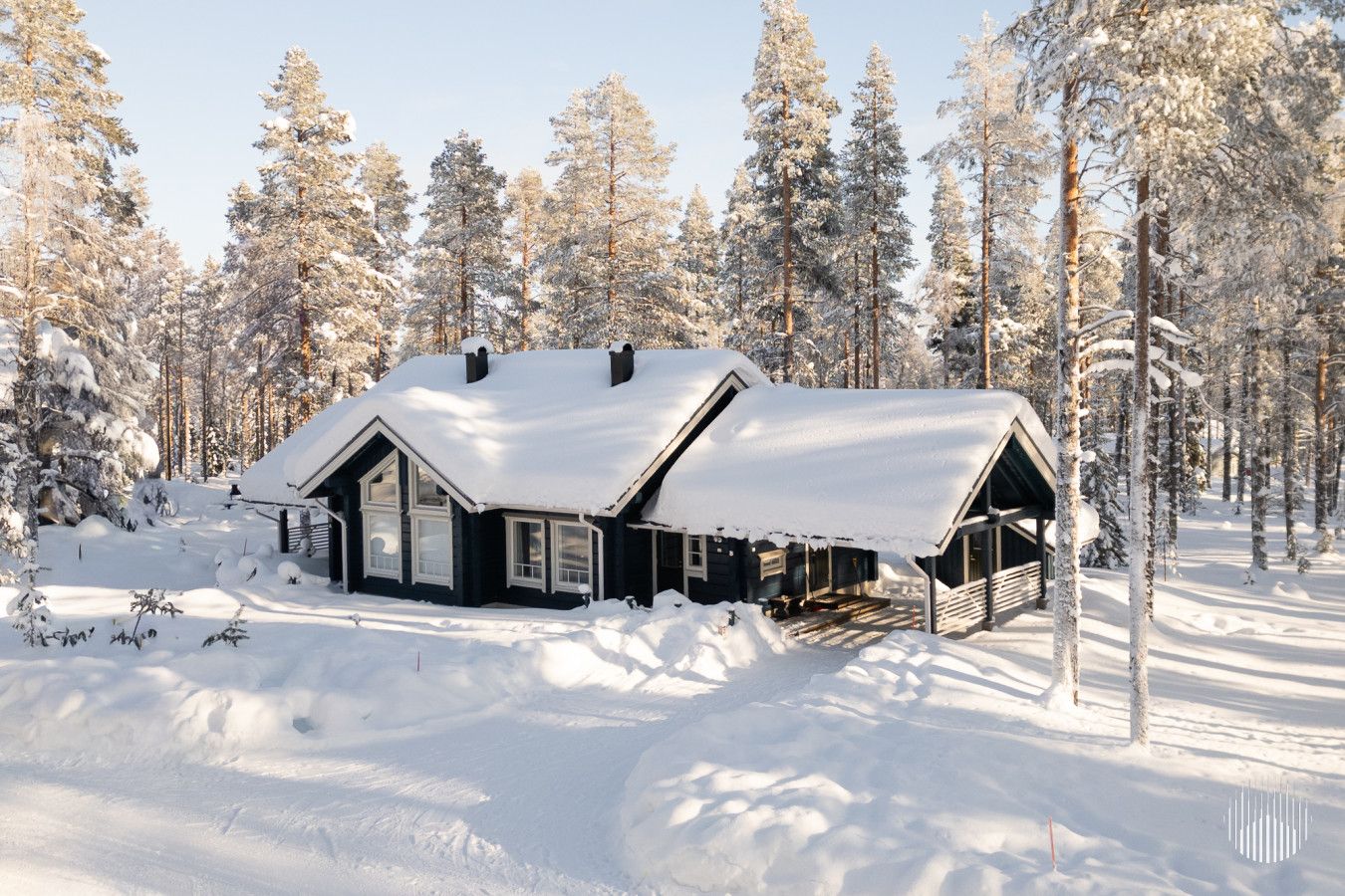 A cabin with a sloped roof, surrounded by snow-covered trees.