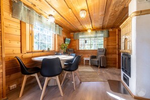 L’intérieur d’un chalet en bois comprend une table de salle à manger ronde, des chaises, une cheminée et un téléviseur.
