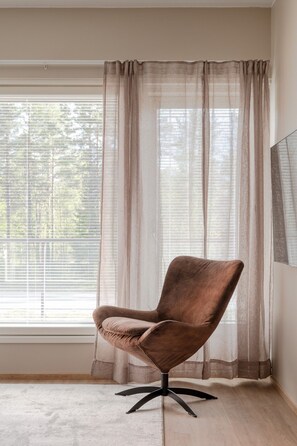 A room with a single brown chair, a window with blinds, and a sheer curtain. - Äkäsentie 1 A 312 by Holiday in Lapland (Äkäslompolo)