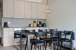 Eine moderne Küche mit hellen Holzschränken, einer zentralen Kochinsel mit Sitzgelegenheit und einer hängenden Pendelleuchte.