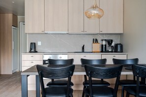 A modern kitchen with light wood cabinets, a central island with black chairs, and a hanging pendant light. - Äkäsentie 1 A 312 by Holiday in Lapland (Äkäslompolo)