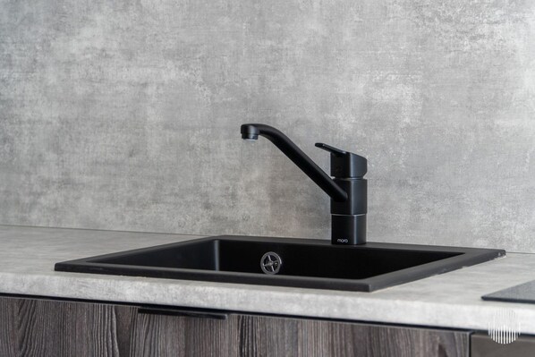 Ein modernes Spülbecken mit elegantem Wasserhahn, einer Arbeitsplatte und einem Holzunterschrank.