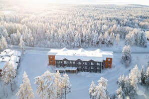 Un grand bâtiment entouré d’arbres couverts de neige, probablement un chalet ou un centre de villégiature.