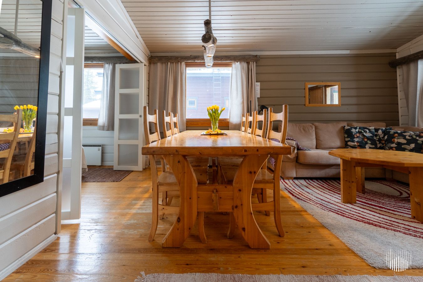 Un coin repas avec une table et des chaises en bois, un canapé et une fenêtre avec des rideaux.