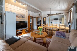 A cozy living room with a sofa, a wooden dining table, and a television. - Kelokaltiokylä 29 by Holiday in Lapland (Ruka)