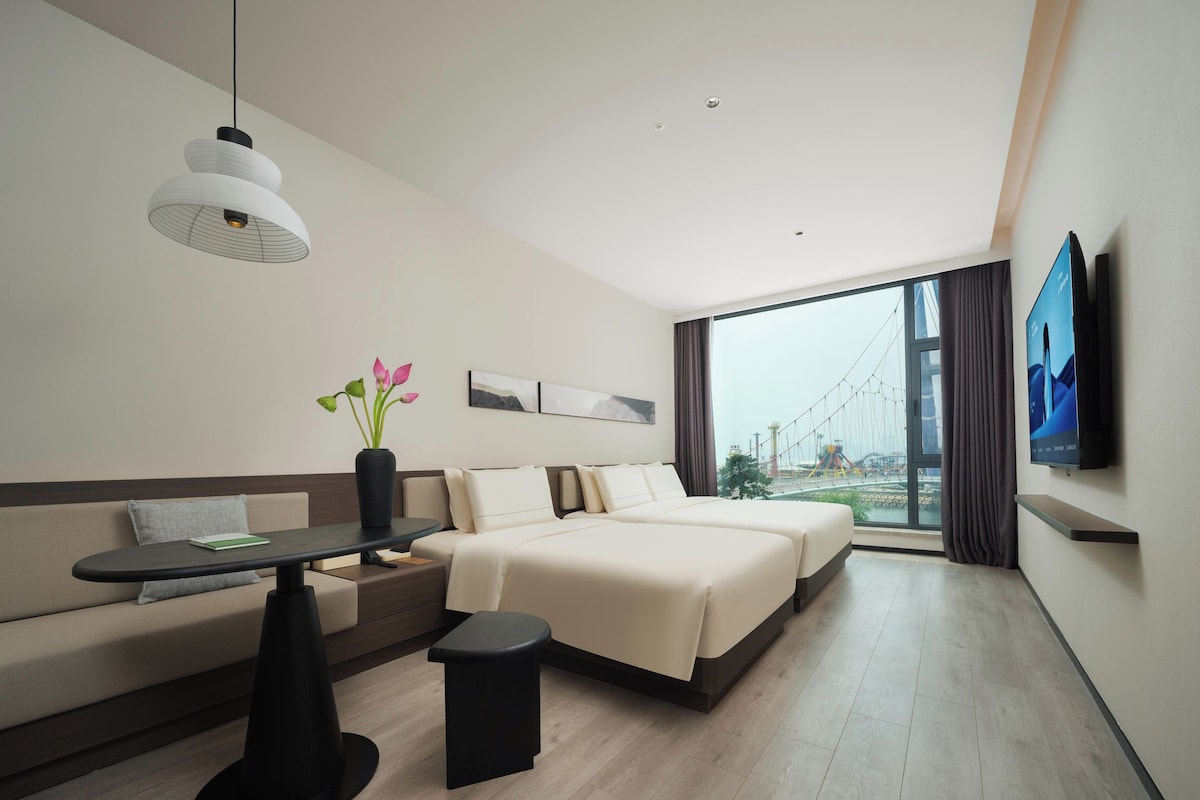 Et moderne hotelværelse med en sofa, en seng, et lille bord, en dekorativ vase og et fjernsyn på væggen.