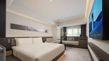 A modern hotel room with a large bed, a desk, a chair, a flat-screen TV, and artwork on the walls.