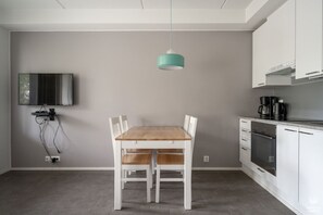 Eine moderne Küche mit weißen Schränken, einem Holztisch und einer türkisfarbenen Pendelleuchte.