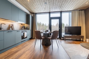 Eine moderne Küche mit grauen Schränken, einem Essbereich mit Tisch und Stühlen sowie einem Fernseher auf einem Schrank.