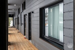 A corridor with grey walls, a wooden floor, and a large window on the right. - Metsonlinna 205 by Holiday in Lapland (Levi)