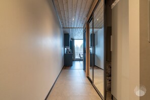 A corridor leading to a kitchen and dining area with a view of the outdoors. - Metsonlinna 205 by Holiday in Lapland (Levi)