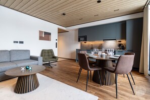 Ein modernes Wohnzimmer mit einer Couch, einem Couchtisch und einem Essbereich mit Stühlen und einem für eine Mahlzeit gedecktem Tisch.