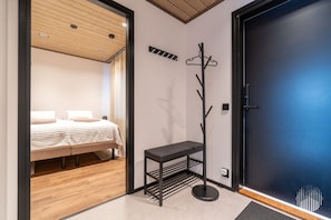 A hotel room with a bed, a coat rack, and a door. - Metsonlinna 205 by Holiday in Lapland (Levi)