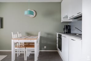 A compact kitchen with a dining table, chairs, a clock, a coffee maker, and a TV. - Sivulantie 4 202 by Holiday in Lapland (Äkäslompolo)