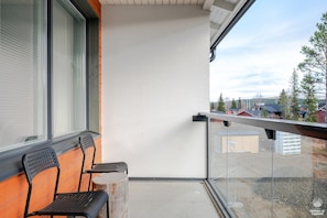 A balcony with two chairs and a small table, overlooking a residential area with houses and trees. - Sivulantie 4 202 by Holiday in Lapland (Äkäslompolo)