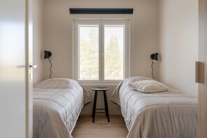 A room with two beds, a window with blinds, a small table, and two wall-mounted lamps. - Äkäsentie 1 A 305 by Holiday in Lapland (Äkäslompolo)