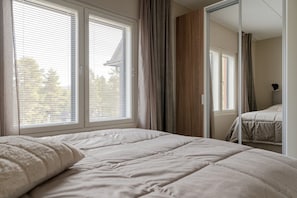 A bedroom with a large bed, two windows with blinds, a mirror, and a view of trees outside. - Äkäsentie 1 A 305 by Holiday in Lapland (Äkäslompolo)